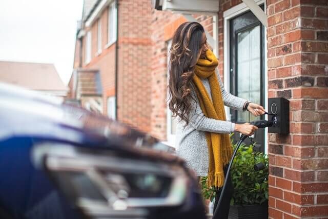 economic-and-environmental | The Interfaith Center for Sustainable Development A woman charging her electric car