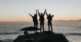 Three friends standing next to the ocean